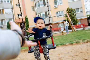 Komik ve yakışıklı çocuk sevinir, salıncakta sallanır, parkta oynar.