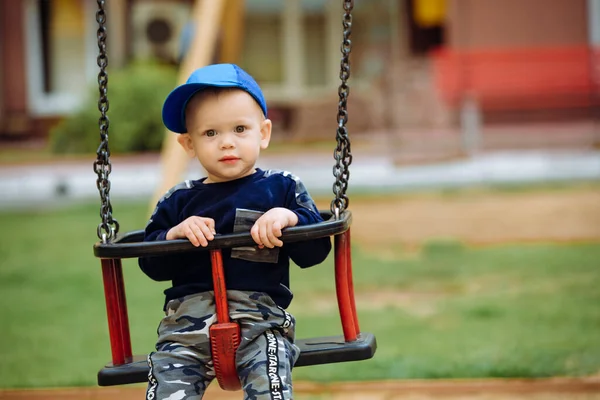 Bonito menino 1-2 anos, sentado em um balanço, playground, close — Fotografia de Stock