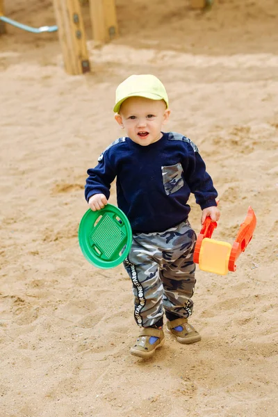 1-2 yaşındaki neşeli bir çocuk oyun parkında oyuncaklarla oynuyor.