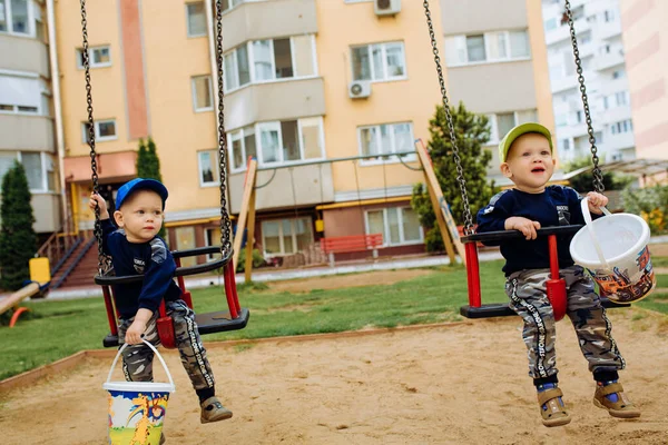 2 irmãos gêmeos andam juntos em um balanço, 1-2 anos — Fotografia de Stock