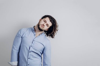 Gömlekli yakışıklı ve uzun saçlı bir adam kameraya bakıyor.