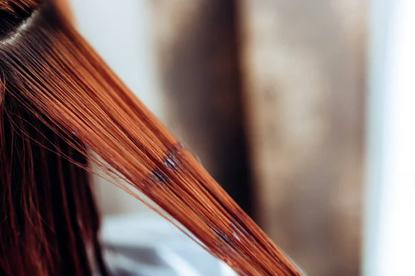 Un coiffeur applique de la peinture sur les cheveux d'une femme dans un salon de beauté. Gros plan . — Photo