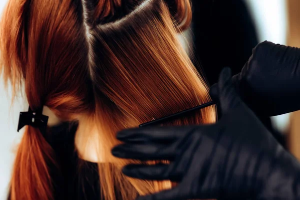 Перукар розчісує руде волосся після процедури . — стокове фото