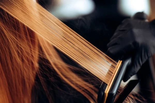 Перукар тягне за волоссям клієнта, після миття голови, наносить поживні речовини на волосся і сушить волосся фен, ботокс волосся, відновлює і живить волосся — стокове фото