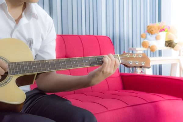 Bir adam tarafından klasik gitar canlı kırmızı uzun sandalyede oturma odasında yumuşak sarı sıcak ışık ile müzik
