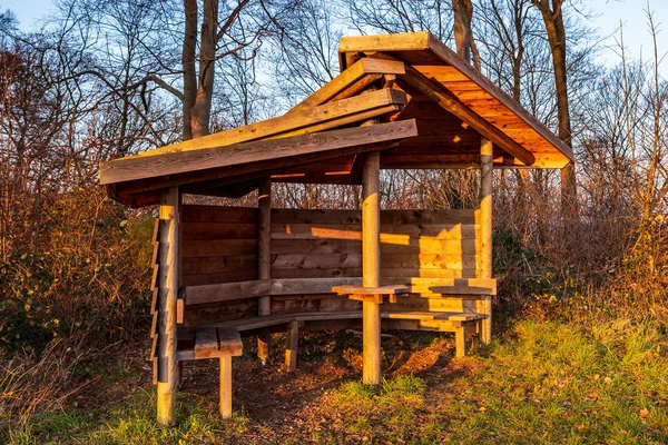 Rest shelter for hikers along the way in the forest in the evening sun