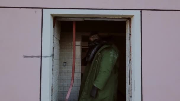 Постапокалипсис, человек в старой разорванной одежде в масках среди разрушенного здания — стоковое видео