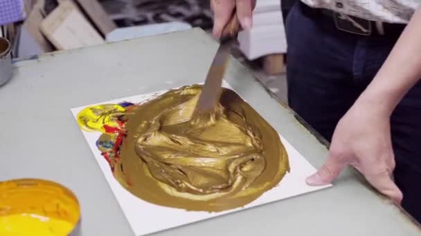 Mann mischt Farbe, bis sie golden ist, um Logo auf Verpackungsprodukte zu drucken — Stockvideo