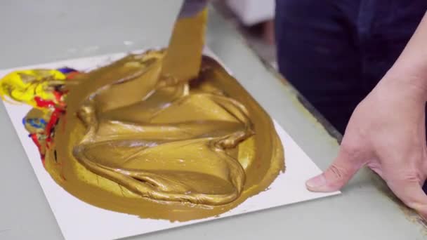 Mann mischt Farbe, bis sie golden ist, um Logo auf Verpackungsprodukte zu drucken — Stockvideo