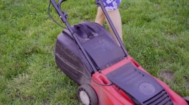 Genç kadın, çim biçme makinesi ile onun owm ev bahçesinde yeşil çim kesme. 4k