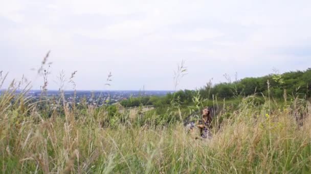 Ung flicka klättrar kullen och samlar in en bukett vildblommor — Stockvideo