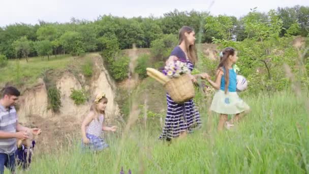 Joven familia feliz con tres hijos que van de picnic en verdes colinas. 4K — Vídeos de Stock