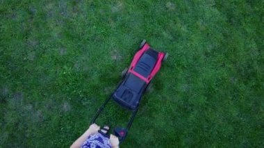 Genç kadın bir yeşil çim çim biçme makinesi ile kendi homeyard içinde mows. 4k