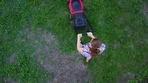 Mujer joven corta una hierba verde en su propio patio con cortacésped. 4K — Vídeos de Stock