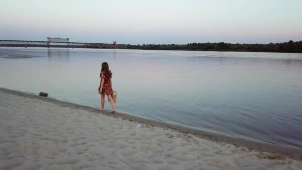강둑의 모래에 매력적인 젊은 여자를 걷으십시오 — 비디오