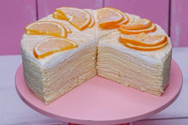 pembe bir arka plan üzerinde beyaz hassas krema ve portakal ile ev yapımı pancake kremalı kek