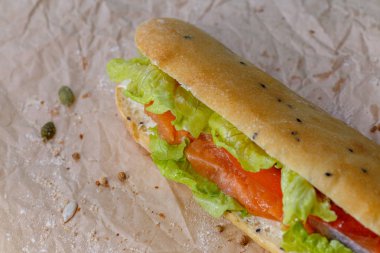 Somon ve sebze, marul ve ev yapımı topuz sos ile Sandviç. Kraft kağıt arka plan üzerinde.