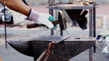 Parlayan sıcak bıçak bladesmith tarafından tutulan ağır bir çekiç tarafından vuruldu. Tanınmayan bir zanaatkârın bıçak dövmesinin sinematik detaylı fotoğrafı. Parlak turuncu çelik sahte oluyor.