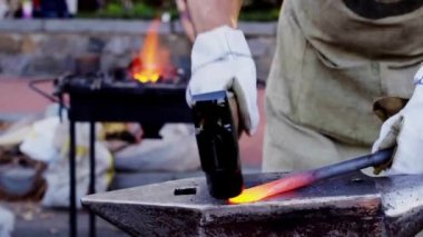 Parlayan sıcak bıçak bladesmith tarafından tutulan ağır bir çekiç tarafından vuruldu. Tanınmayan bir zanaatkârın bıçak dövmesinin sinematik detaylı fotoğrafı. Parlak turuncu çelik sahte oluyor.