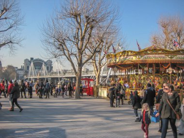 Londra /England / İngiltere - 02/19/2013: Londra, Thames Nehri'nin güney yakasına sokak sanatçıları ve klasik bir atlıkarınca, birçok insan turist ile görünümünü