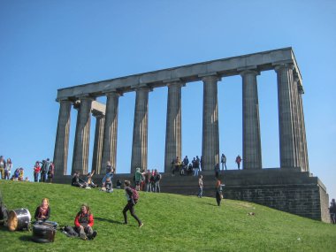 Edinburgh / İskoçya / İngiltere - 04 / 20 / 2014: İskoçya Ulusal Anıtı 'nın Edinburgh' daki Calton Hill 'de manzarası, etrafındaki çimenler ve insanların tadını çıkarmasıyla