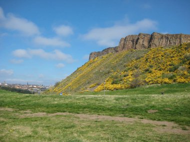 Edinburgh / İskoçya / Uk - 04/20/2014: Holyrood parkın görünümü Salisbury crags yeşil alanlar, yürüyüş ve seyir, arka plan üzerinde mavi gökyüzü Edinburgh turist ile
