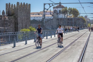 Porto/Portekiz-10/02/2018: Metro demiryolu parça D. Luis köprüde Bisiklete binme iki adam arka plan Ortaçağ duvar ve manastır olarak