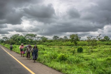 Malange / Angola - 12 08 2018: Angola'nın toprakları 2018 yolculuk: yaşlı kadın çiftçiler, tipik tropikal manzara arka plan olarak yolun kenarında yürüyüş görünümünü