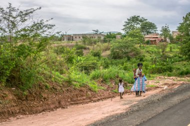 Malange / Angola - 12 08 2018: Çocuklu kadınla görünümünü yürür arka plan olarak yol kenarı, tipik Afrika köy boyunca