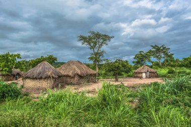 Geleneksel köy, thatched çatı ve pişmiş toprak ve saman duvarlar, evin arka plan olarak bulutlu gökyüzü görünümü