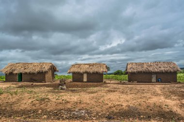 Geleneksel köy, thatched evlerin çatı ve pişmiş toprak tuğla duvarlı, arka plan, Angola olarak bulutlu gökyüzü görünümü