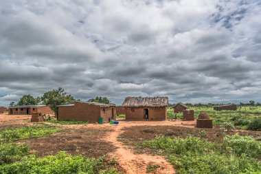 Malange / Angola - 12 08 2018: geleneksel köy thatched, görünümünü evler çatı ve pişmiş toprak tuğla duvarlar, dışında bulutlu gökyüzü arka plan olarak oynayan çocuklar
