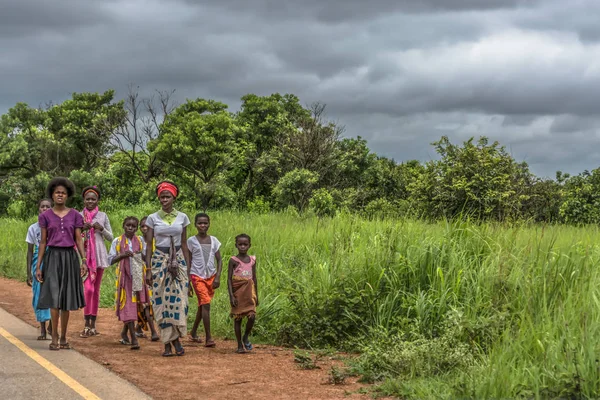 Malange / Angola - 12 08 2018: bir grup genç kızlar arka plan olarak yol kenarı, tropikal peyzaj boyunca yürüyüş, görünümünü