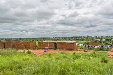 Malange / Angola - 12 08 2018: geleneksel köy, insanların görünümünü ve thatched ve çinko levha çatı evleri ve pişmiş toprak tuğla duvarlar, arka plan, Angola olarak bulutlu gökyüzü