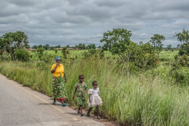 Malange / Angola - 12 08 2018: iki çocuklu kadınla görünümünü yürüyüşleri boyunca yol kenarı, tropikal manzara arka plan olarak