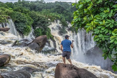 Malange / Angola - 12 08 2018: Kalandula çağlayan bir kaya üzerinde, bir aksiyon kamerası ile filme adam görünümü