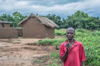 Malange / Angola - 12 08 2018: bir dostu görünümünü dostum ile sigara elinde, aşiret Köyü, orman ve dramatik gökyüzü arka plan olarak evinde yanındaki