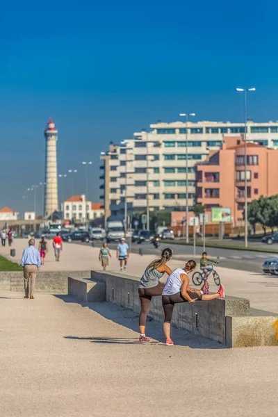 View of the beach of Leca da Palmeira, with people doing exercise and walking, on coast next to the beach, lighthouse in the background — Stock Photo, Image