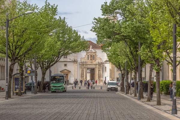 Uitzicht op een plein, met ijzeren poort van de Universiteit van Coimbra, klassieke architectonische structuur met metselwerk, met mensen, bomen en voertuigen, toren van de Universiteit van Coimbra als achtergrond, in Portug — Stockfoto