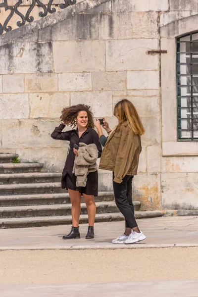Vista de mulheres perto da escadaria do edifício da Universidade de Direito em Coimbra, a falar e a tirar fotografias com o telemóvel, em Portugal — Fotografia de Stock