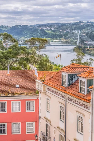 Widok na tradycyjne klasyczne budynki, z niewyraźne Mondego rzeki i Rainha Santa Isabel Bridge jako tło w Coimbra, Portugalia — Zdjęcie stockowe