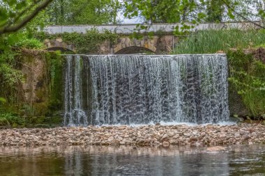 Arka plan olarak eski köprü ile, ormanda nehir küçük şelale görünümü