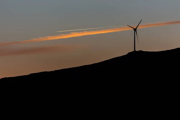 Vue en silhouette d'une éolienne au sommet des montagnes, ciel couchant — Photo