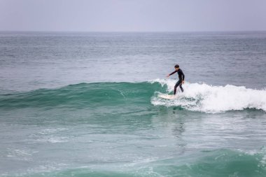 Dalgalar ile denizde aşırı manevralar yapan profesyonel sörfçü ile Plaj görünümü