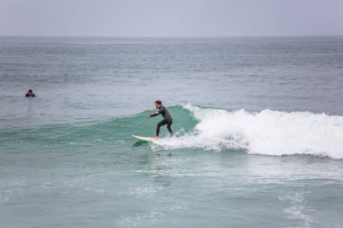 Dalgalar ile denizde aşırı manevralar yapan profesyonel sörfçü ile Plaj görünümü