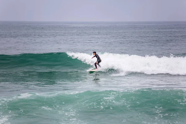 Vista a la playa con surfistas profesionales haciendo maniobras extremas en el mar con olas —  Fotos de Stock