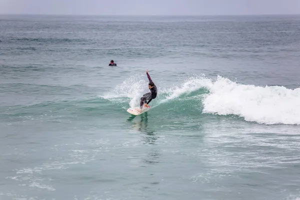 Výhled na pláž s profesionálními surfaři, kteří dělají extrémní manévry na moři s vlnami — Stock fotografie