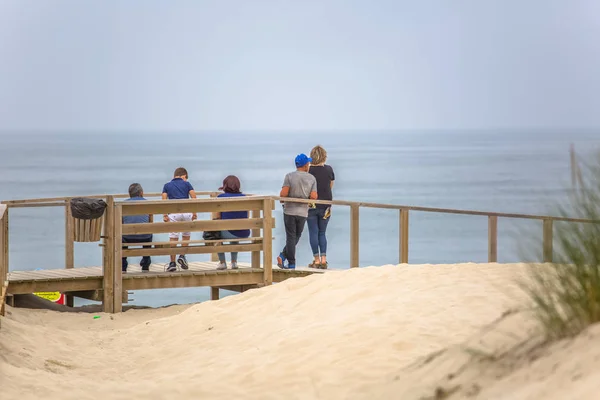 Widok na ścieżkę dla pieszych na plaży, plecy rodzinnego siedzenia na ławce i patrząc do morza na drewnianej ścieżce, morze jako tło — Zdjęcie stockowe