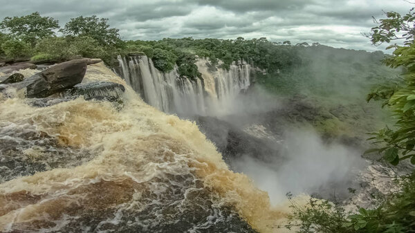 View of the Kalandula waterfalls on Lucala river, tropical forest and cloudy sky as background
