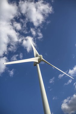 Dağların tepesinde bir rüzgar türbini, arka planda mavi gökyüzü